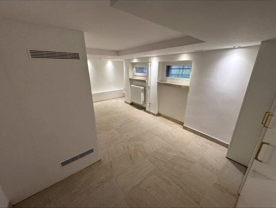 Ausgebauter, heller Kellerraum mit neuem Fliesenboden und kleinen Kellerfenstern